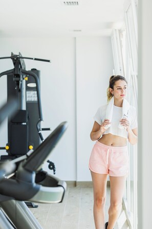 A person in a gym with exercise equipment, a window, and a white wall. - Apartamentos Martalia Nerja (Torrox)