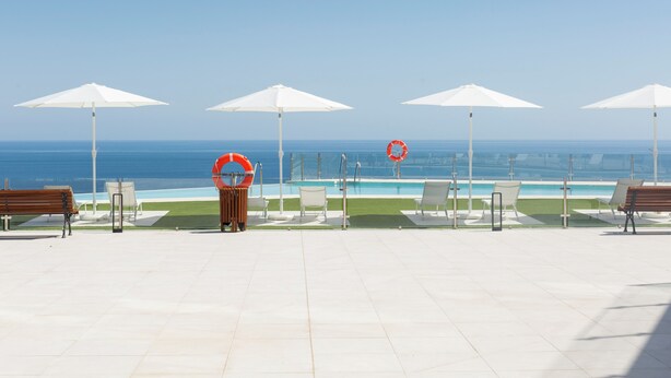 A poolside area with white umbrellas, lounge chairs, and a lifebuoy. - Apartamentos Martalia Nerja (Torrox)