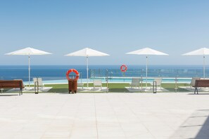 A poolside area with white umbrellas, lounge chairs, and a lifebuoy. - Apartamentos Martalia Nerja (Torrox)