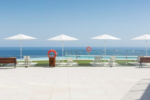 A poolside area with white umbrellas, lounge chairs, and a lifebuoy.