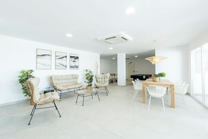 Una sala de estar moderna con un conjunto de sofás, una mesa de comedor con sillas y un ventanal que proporciona luz natural.