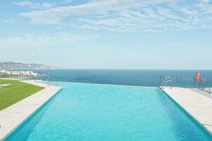 A swimming pool with a clear view of the ocean and a distant mountain range.