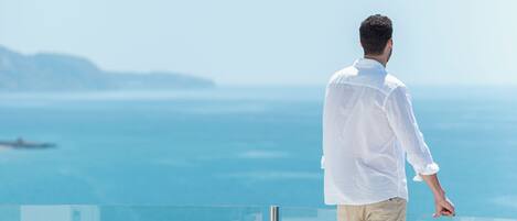 A man standing on a balcony overlooking a body of water.