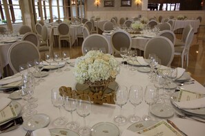 A banquet hall with round tables set for a formal event, featuring white tablecloths, glassware, and floral centerpieces. - Snö Pazo de Adran (Teo)