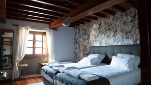 A bedroom with a bed, a window with curtains, a wall with floral wallpaper, and a chandelier. - Snö Pazo de Adran (Teo)