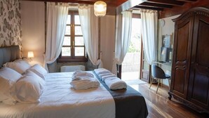 A bedroom with a large bed, a wooden wardrobe, and a desk with a chair. - Snö Pazo de Adran (Teo)