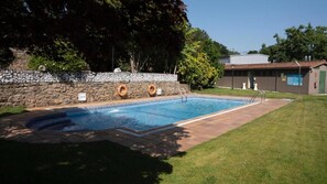 A rectangular swimming pool with a stone wall and a grassy area in the foreground. - Snö Pazo de Adran (Teo)