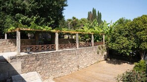 A stone wall with a wooden deck and a pergola with climbing plants. - Snö Pazo de Adran (Teo)