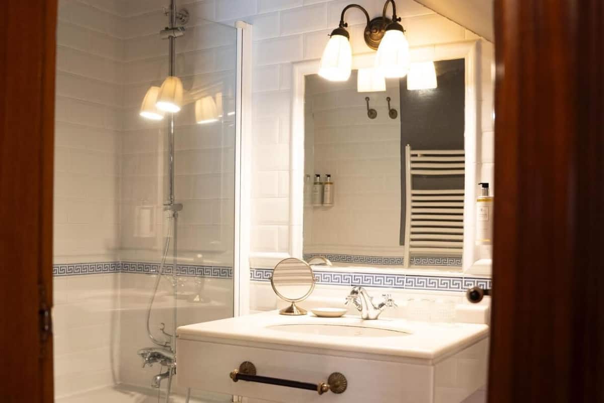 A bathroom with a bathtub, a sink with a mirror, and a shower.