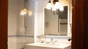 A bathroom with a bathtub, a sink with a mirror, and a shower. - Snö Pazo de Adran (Teo)