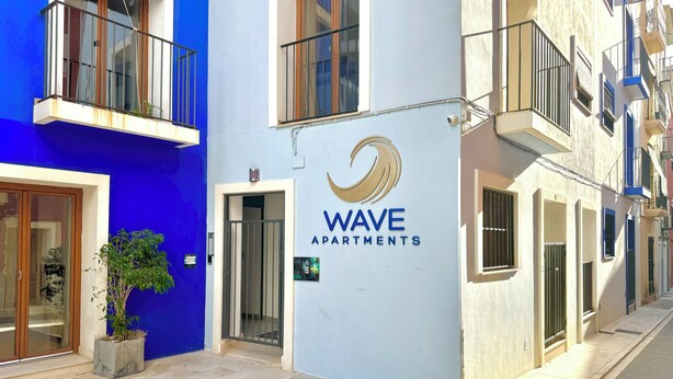 Un edificio con fachada azul y un letrero que dice "WAVE APARTMENTS".