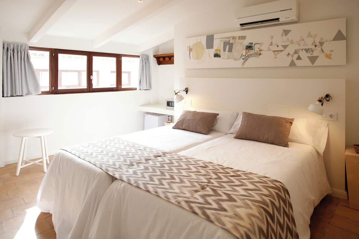 A bedroom with two beds, a desk, and a chair.