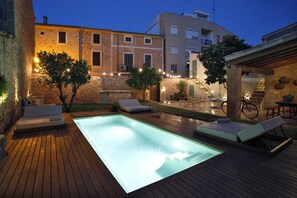 A swimming pool with lounge chairs, a wooden deck, and a stone building in the background. - Ca Sa Tieta (Alaro)