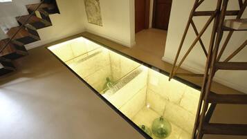 Un interior moderno con un atrio de suelo de cristal, una escalera de madera y un diseño minimalista.