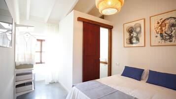 Un dormitorio con una cama, una puerta de madera y dos cuadros en la pared.