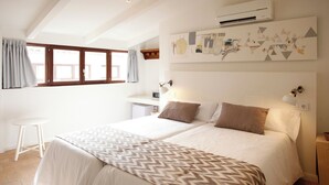 Une chambre avec deux lits, un petit bureau, une chaise et un climatiseur fixé au mur.