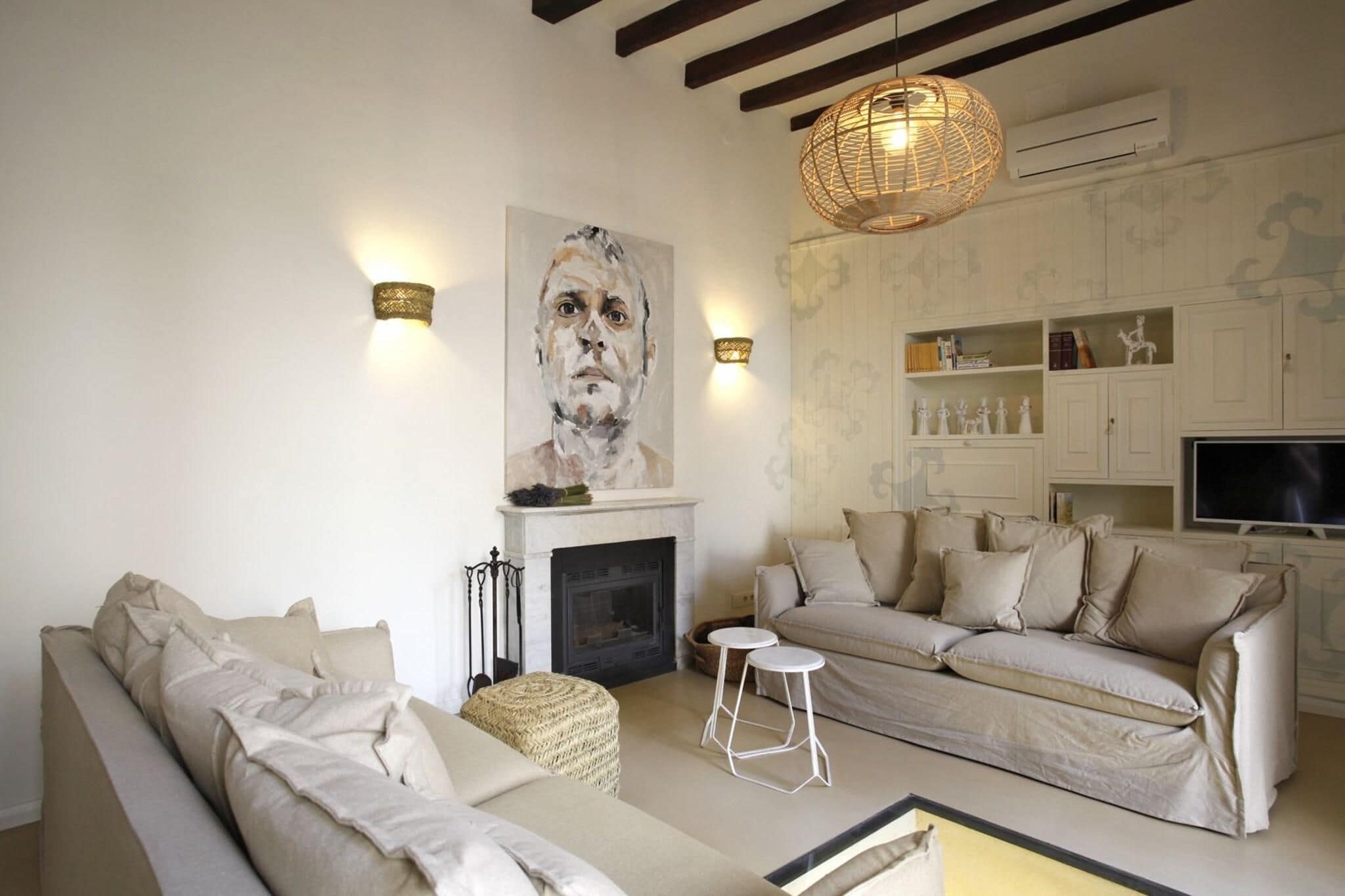 Una sala de estar con chimenea, dos sofás, un televisor y apliques decorativos en la pared.
