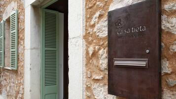 Una placa de metal con la inscripción "ca sa tieta" y "TOURME D'INTERIOR" sobre una pared de piedra texturizada.