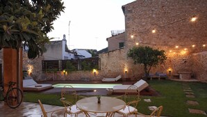 A patio with a round table and chairs, a small pool, and stone walls. - Ca Sa Tieta (Alaro)