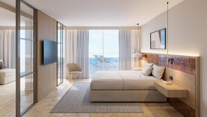 A modern hotel room with a large bed, a TV, a desk, and a view of the ocean. - Estival Maramar (El Vendrell)