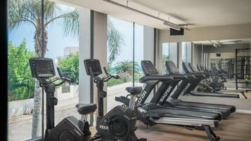Un gimnasio con cintas de correr, bicicletas estáticas y elípticas.
