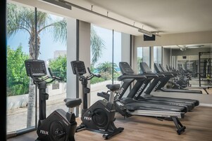 Un gimnasio con cintas de correr, bicicletas estáticas y elípticas.
