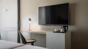 A hotel room with a bed, a desk with a lamp, a flat-screen TV, and a coffee maker.