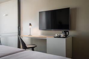 A hotel room with a bed, a desk with a lamp, a flat-screen TV, and a coffee maker. - Estival Maramar (El Vendrell)