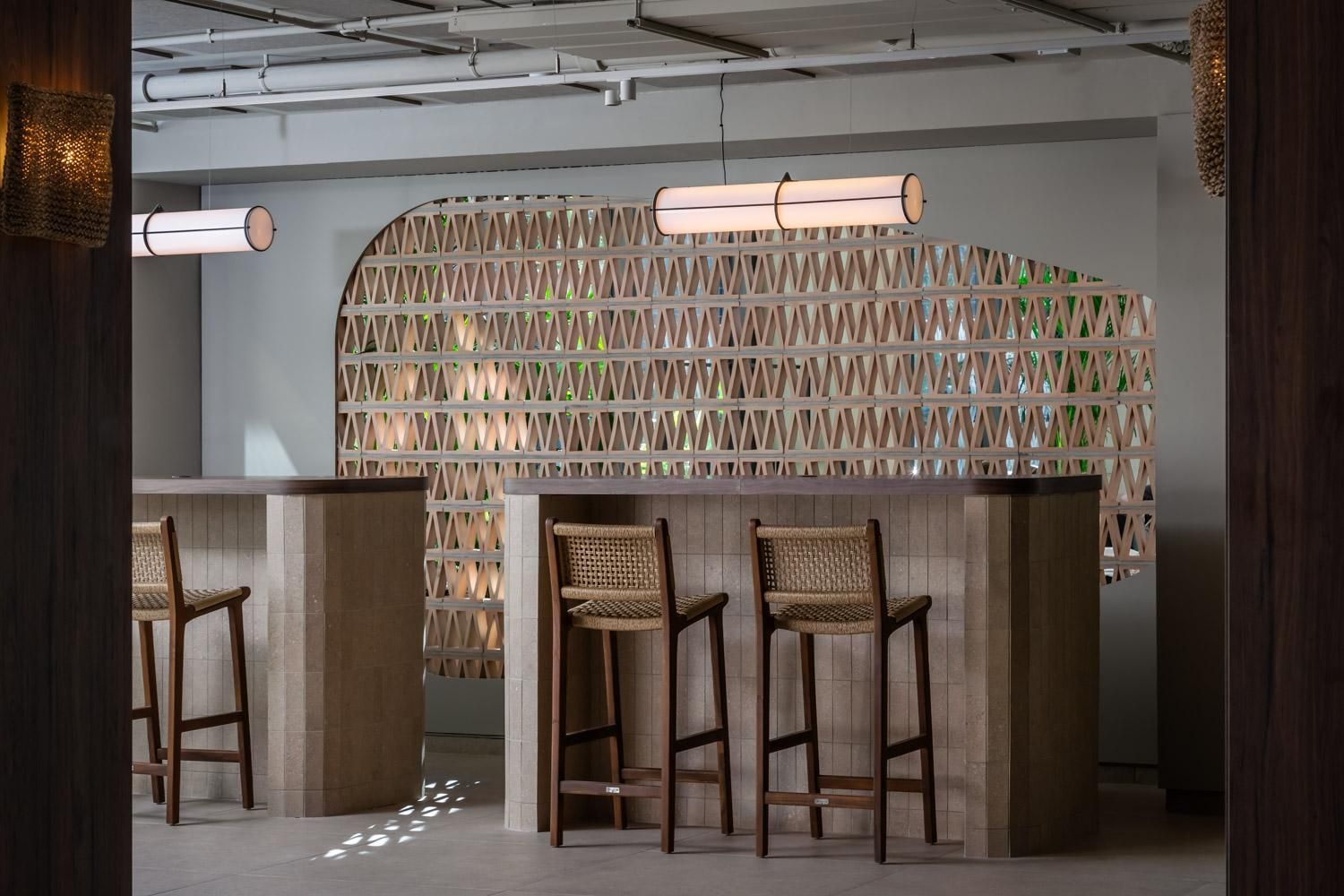 Un bar moderno con tres taburetes de madera y una lámpara colgante.