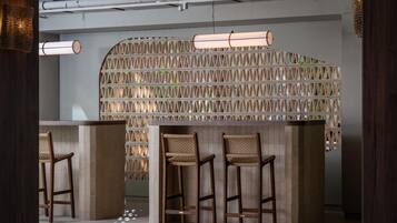 Un bar moderno con tres taburetes de madera y una lámpara colgante.