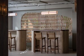 A modern bar area with three wooden stools and a light fixture above. - Estival Maramar (El Vendrell)