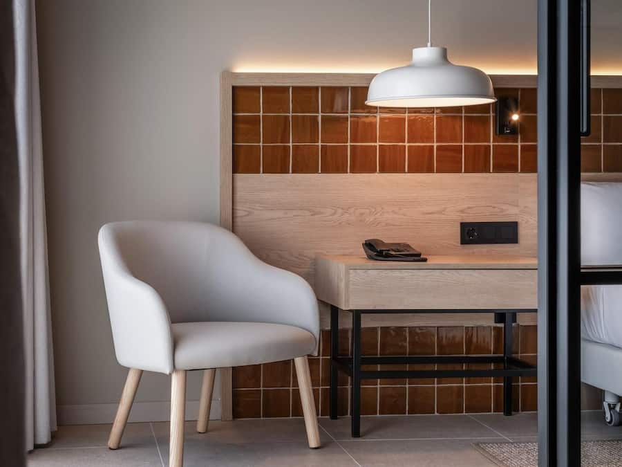 Una habitación moderna con una silla blanca, un escritorio de madera y una lámpara colgante blanca.