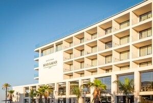 Um hotel moderno de vários andares, com varandas em cada pavimento e céu claro.