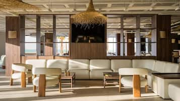 Una sala moderna con un amplio sofá modular, mesas de centro de madera y lámparas de mimbre colgantes.