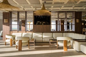 A modern living room with a large sectional sofa, wooden coffee tables, and hanging wicker lamps. - Estival Maramar (El Vendrell)