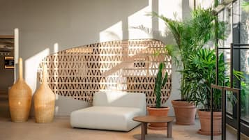 A modern interior with a white sofa, two wicker vases, a wooden lattice wall, and potted plants.