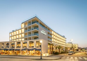 A modern hotel with multiple floors, outdoor seating, and a well-lit facade. - Estival Maramar (El Vendrell)