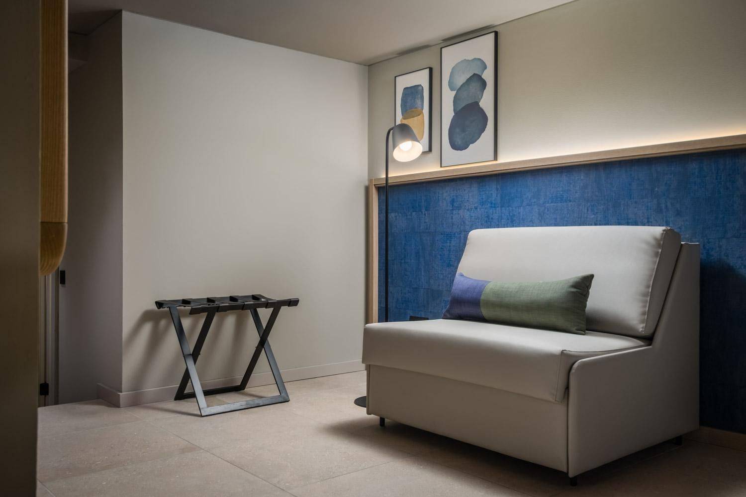 A modern living room with a white sofa, a small table, and abstract art on the wall.