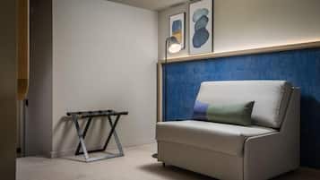 A modern living room with a white sofa, a small table, and abstract art on the wall.