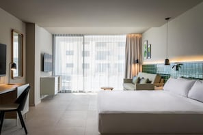A modern hotel room with a large bed, a desk with a chair, a sofa, and a TV. - Estival Maramar (El Vendrell)