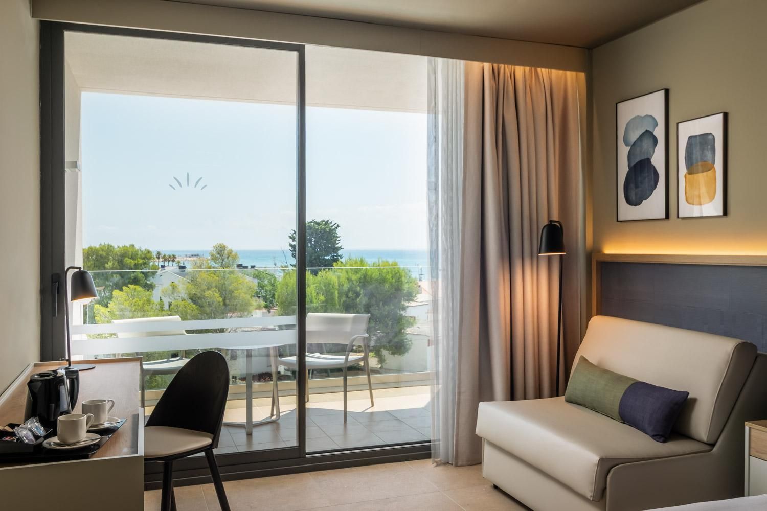 Una habitación de hotel con balcón, sofá, escritorio y una silla.