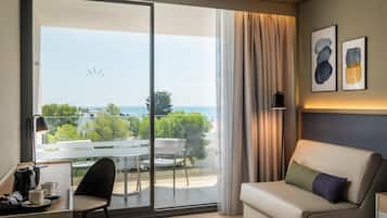 Una habitación de hotel con balcón, sofá, escritorio y una silla.