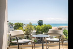 A balcony with two chairs and a small table, overlooking a coastal view with buildings and trees. - Estival Maramar (El Vendrell)