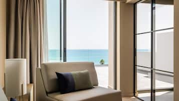 A hotel room with a view of the ocean, a sofa, and a lamp.