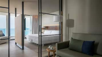 Una habitación de hotel moderna con una cama, un sofá, una mesita y vista al mar.