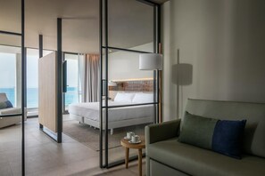 A modern hotel room with a bed, a sofa, a small table, and a view of the sea. - Estival Maramar (El Vendrell)