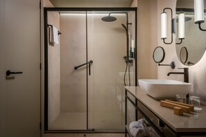 A modern bathroom with a glass-enclosed shower, a large sink, and a vanity with toiletries. - Estival Maramar (El Vendrell)