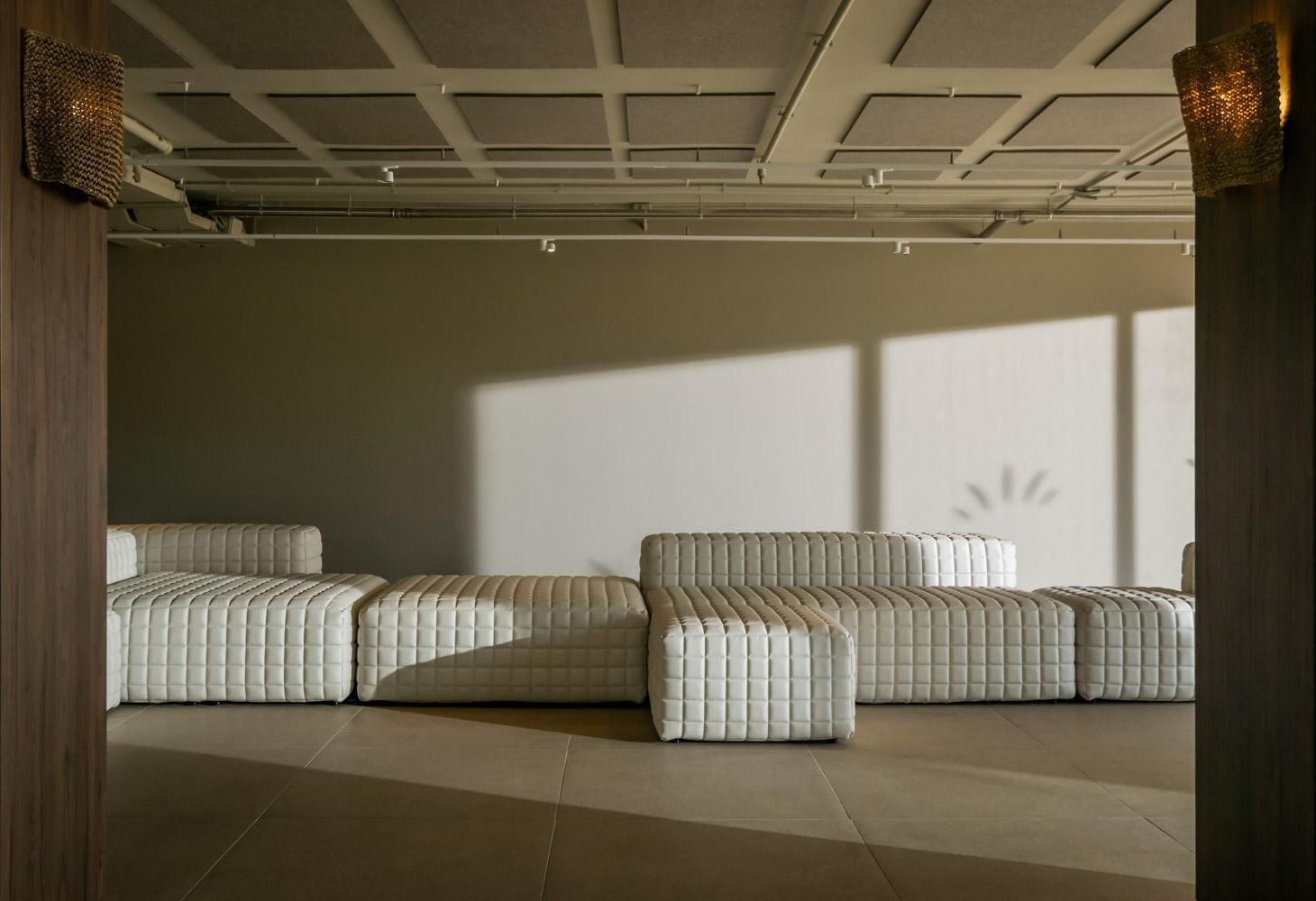 Una habitación moderna y minimalista con sofá modular y un amplio ventanal que proporciona luz natural.
