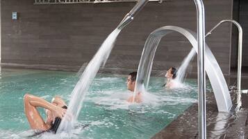 A swimming pool with multiple water jets, a tiled wall with text, and a metal railing.