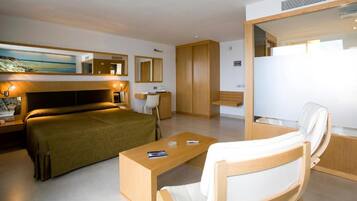 Una habitació d'hotel moderna amb un llit, una taula de treball, una cadira, un armari i un quadre a la paret.